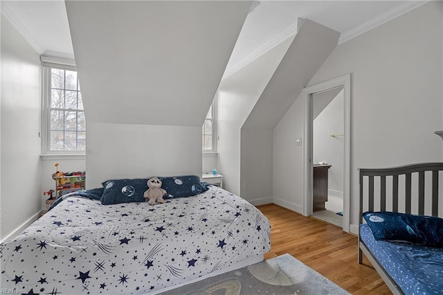 bedroom featuring lofted ceiling, crown molding, baseboards, and wood finished floors