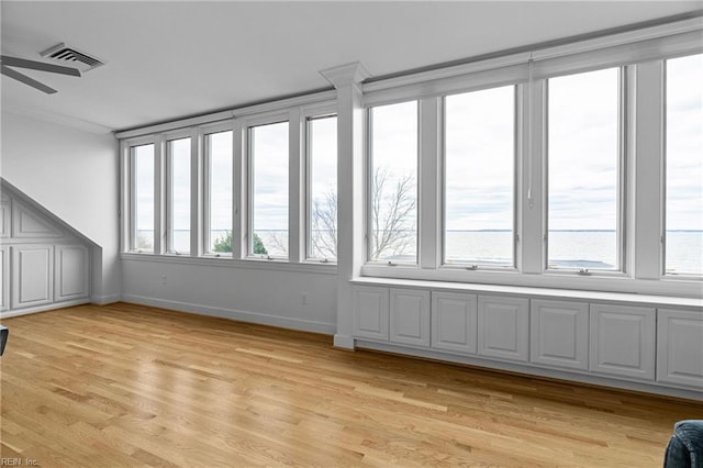 unfurnished sunroom featuring a wealth of natural light, visible vents, and ceiling fan