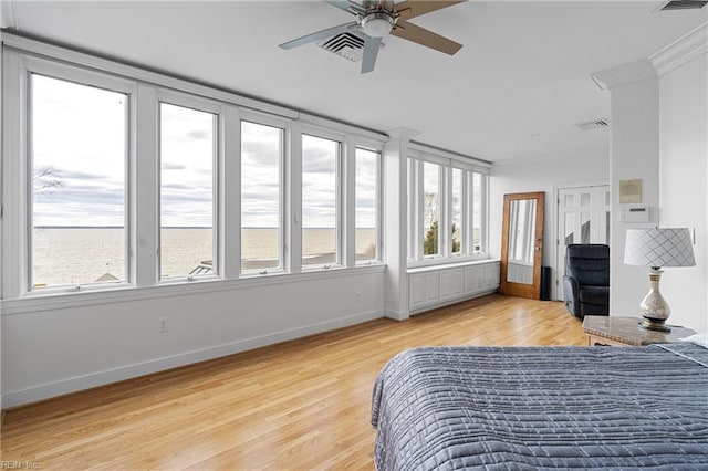 bedroom with visible vents, baseboards, light wood-style floors, and ornamental molding