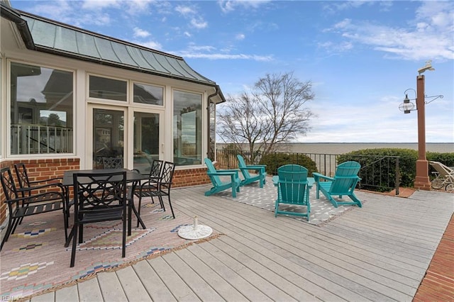 wooden terrace featuring outdoor dining area and a sunroom