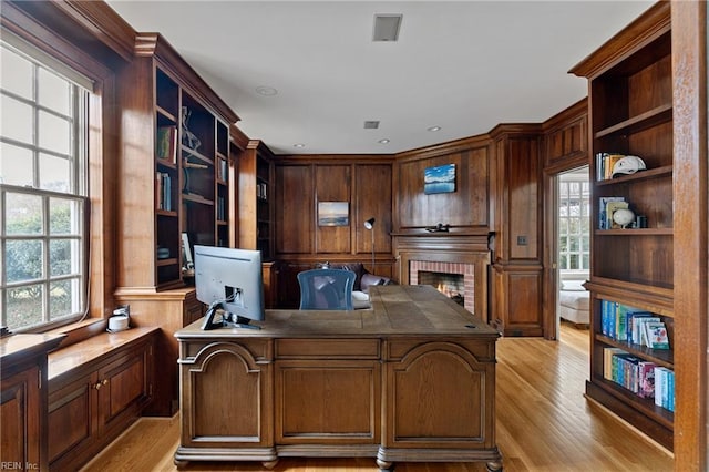 home office with plenty of natural light, light wood-style floors, and a brick fireplace