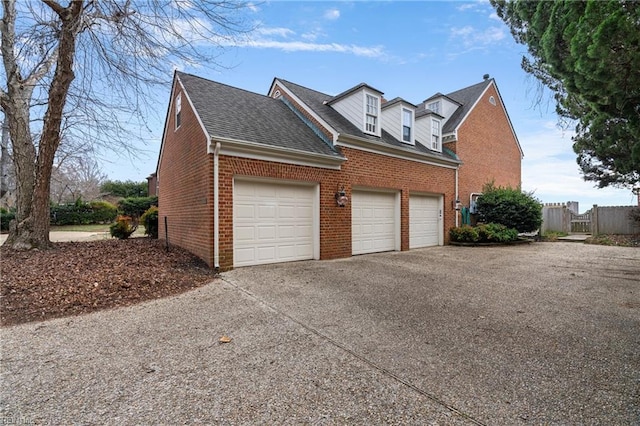 view of home's exterior with brick siding, driveway, a garage, and roof with shingles