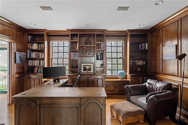 office featuring a wealth of natural light, built in shelves, and light wood-style floors