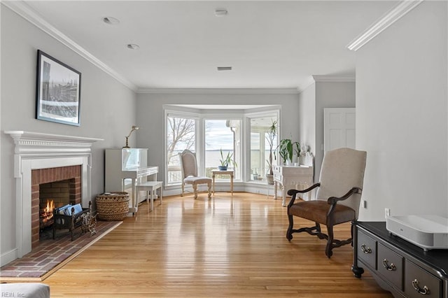 living area featuring a fireplace, light wood-style floors, and ornamental molding