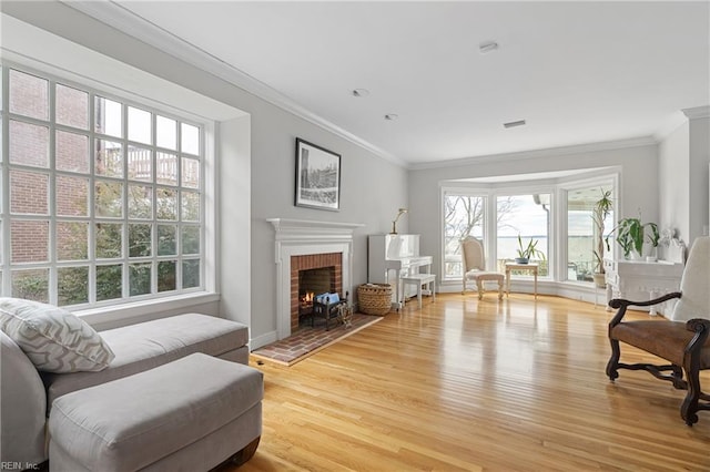 living area featuring light wood-type flooring, baseboards, a brick fireplace, and crown molding