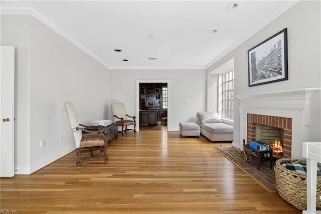 sitting room featuring a fireplace, light wood-style floors, and ornamental molding