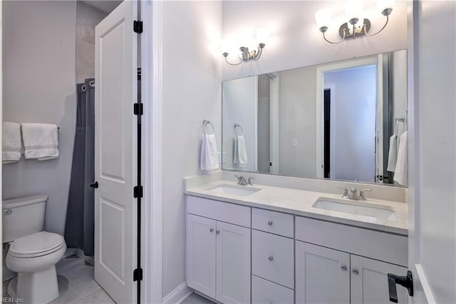 bathroom with double vanity, toilet, baseboards, and a sink