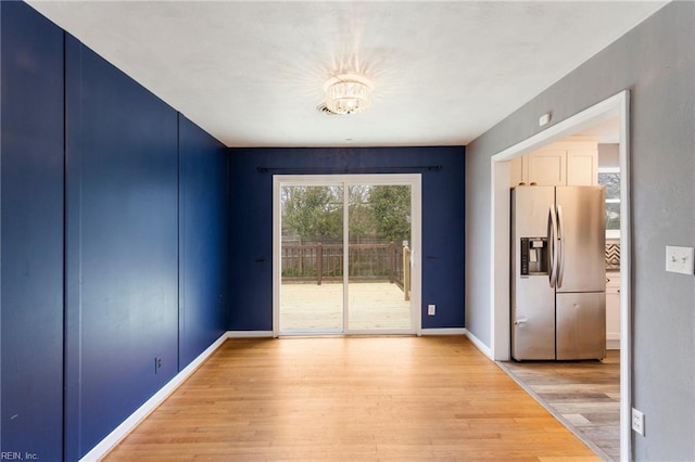 unfurnished dining area with light wood-style flooring, baseboards, and a chandelier