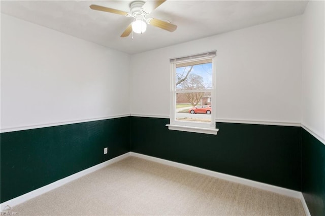 carpeted spare room featuring baseboards and ceiling fan