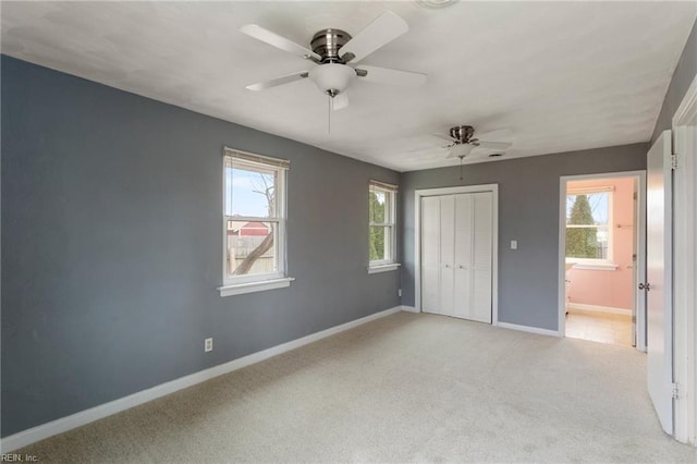 unfurnished bedroom featuring a closet, light colored carpet, a ceiling fan, and baseboards