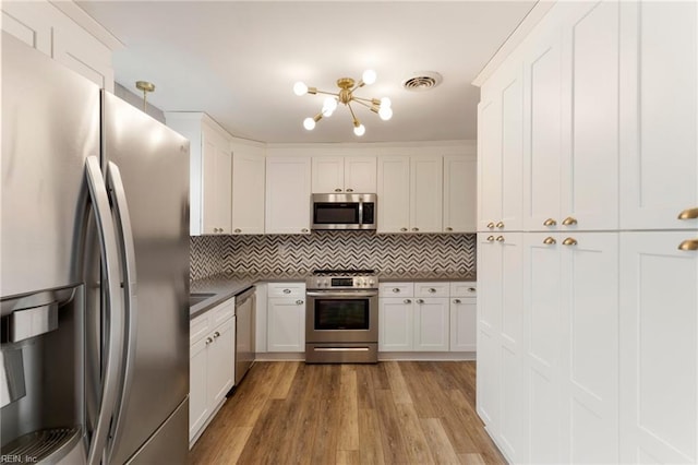 kitchen featuring dark countertops, visible vents, a chandelier, appliances with stainless steel finishes, and wood finished floors