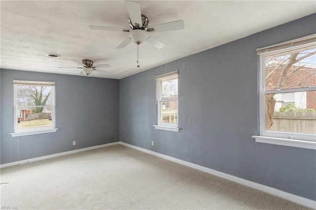 carpeted empty room with visible vents, a ceiling fan, and baseboards