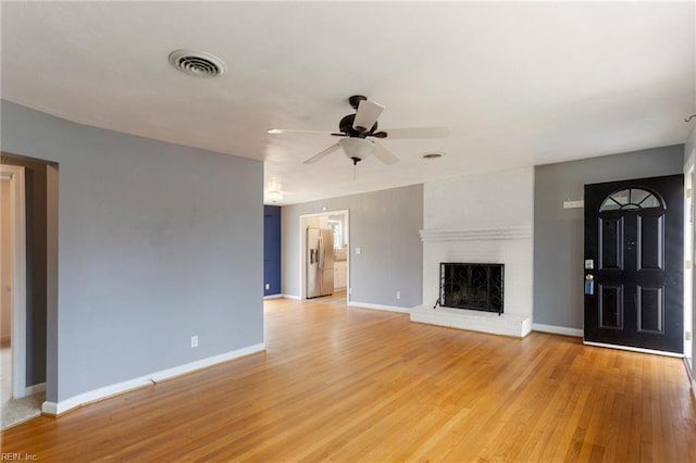 unfurnished living room featuring visible vents, baseboards, light wood-style flooring, a fireplace, and a ceiling fan