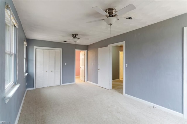 unfurnished bedroom with visible vents, baseboards, light carpet, a closet, and a ceiling fan