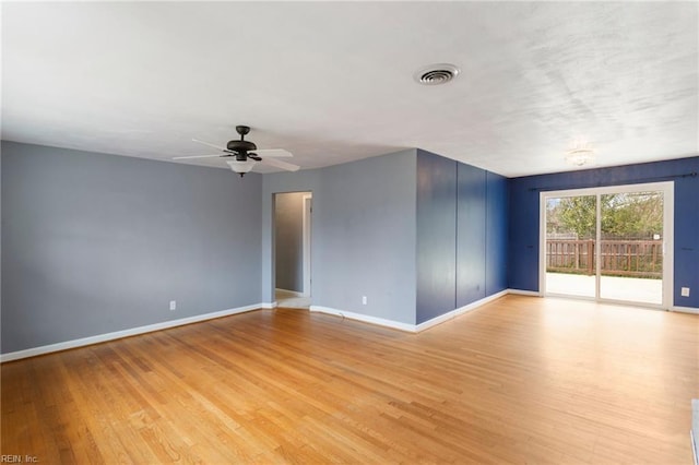 spare room with a ceiling fan, visible vents, light wood-type flooring, and baseboards