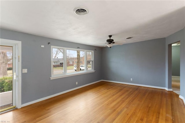 unfurnished room with light wood finished floors, visible vents, a ceiling fan, and baseboards