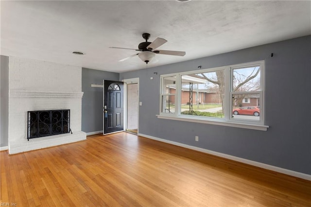 unfurnished living room with visible vents, ceiling fan, baseboards, a fireplace, and wood finished floors