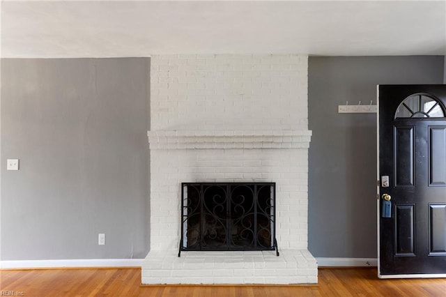 room details with baseboards, a brick fireplace, and wood finished floors