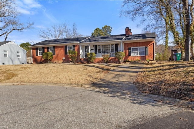 view of front of home featuring brick siding, a porch, and a chimney