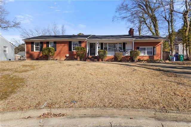 ranch-style house featuring brick siding, covered porch, and a chimney