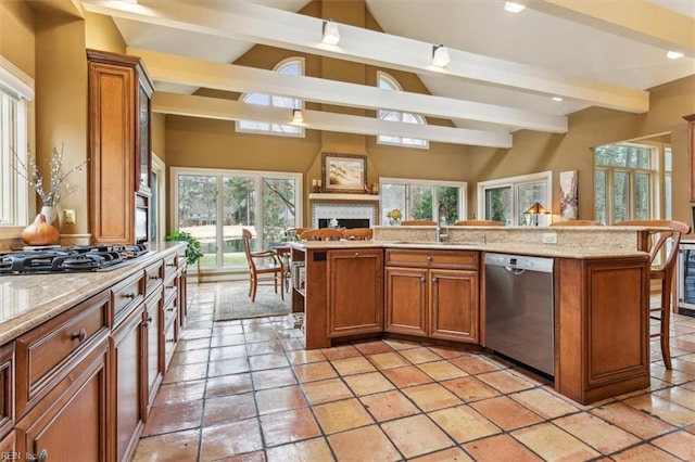 kitchen with a breakfast bar, stainless steel dishwasher, brown cabinetry, gas stovetop, and a sink