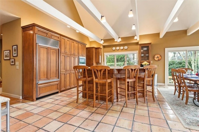 dining room featuring beamed ceiling, baseboards, and a healthy amount of sunlight