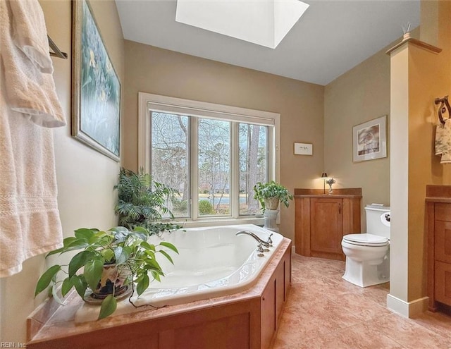 full bathroom featuring vanity, a skylight, toilet, and a bath