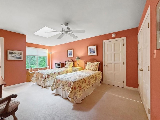 carpeted bedroom featuring a skylight and ceiling fan