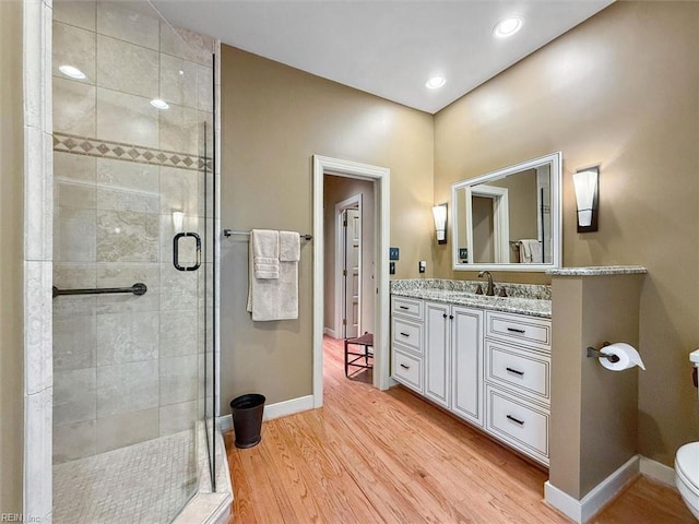 bathroom with vanity, wood finished floors, baseboards, a stall shower, and toilet