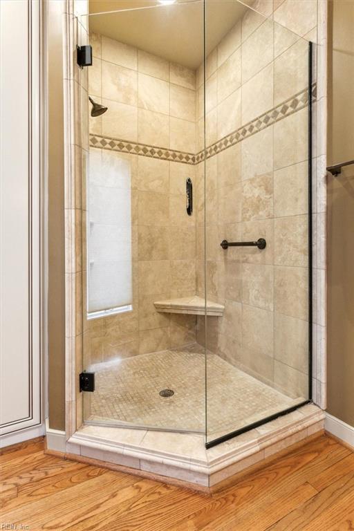 full bathroom featuring baseboards, wood finished floors, and a stall shower