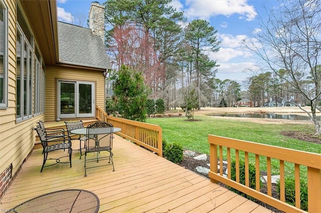 wooden deck featuring a yard, a water view, and outdoor dining space