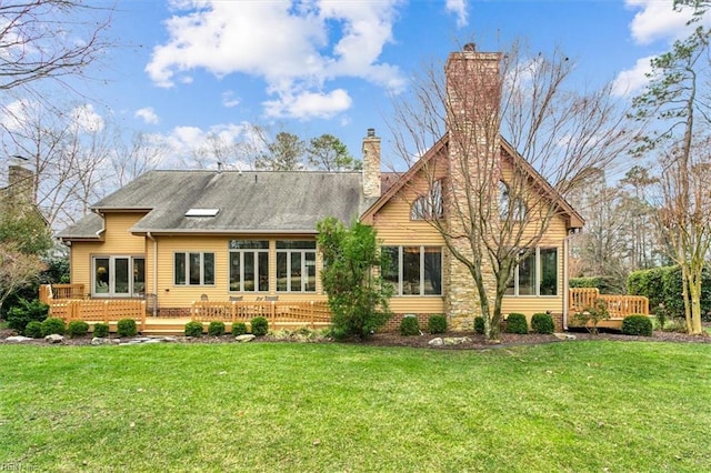 rear view of property with a yard, a deck, and a chimney