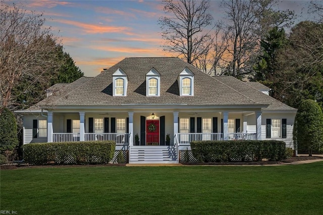 view of front of house featuring covered porch, a front lawn, and a shingled roof