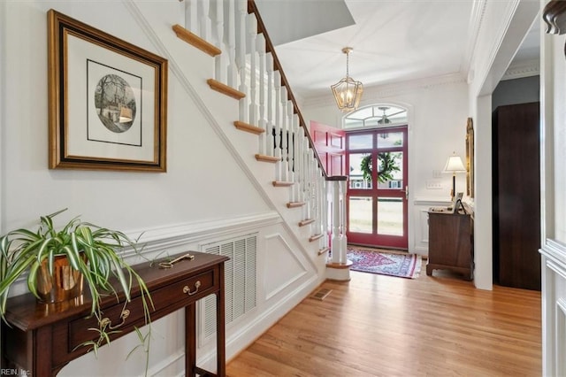 entrance foyer with stairs, crown molding, visible vents, and an inviting chandelier