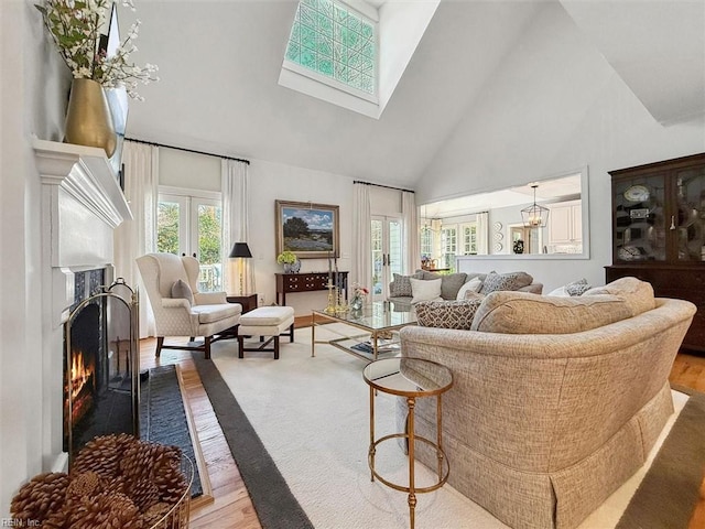 living area featuring a skylight, plenty of natural light, a warm lit fireplace, and high vaulted ceiling