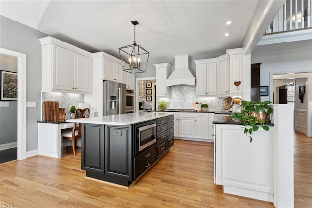 kitchen featuring stainless steel appliances, custom exhaust hood, and white cabinetry