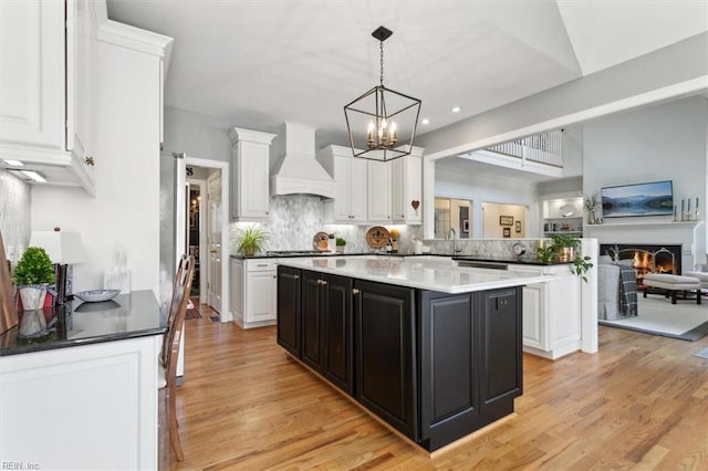 kitchen with white cabinets, dark cabinetry, an inviting chandelier, and premium range hood