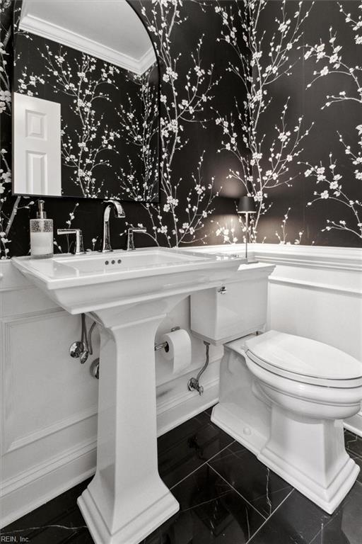 bathroom with marble finish floor, wallpapered walls, toilet, and crown molding