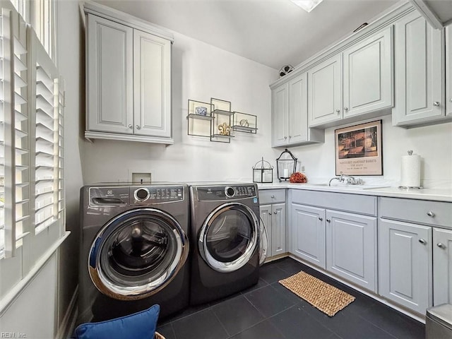 laundry area with a sink, cabinet space, dark tile patterned flooring, and washer and clothes dryer