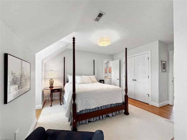 bedroom with a closet, visible vents, light wood-type flooring, and baseboards