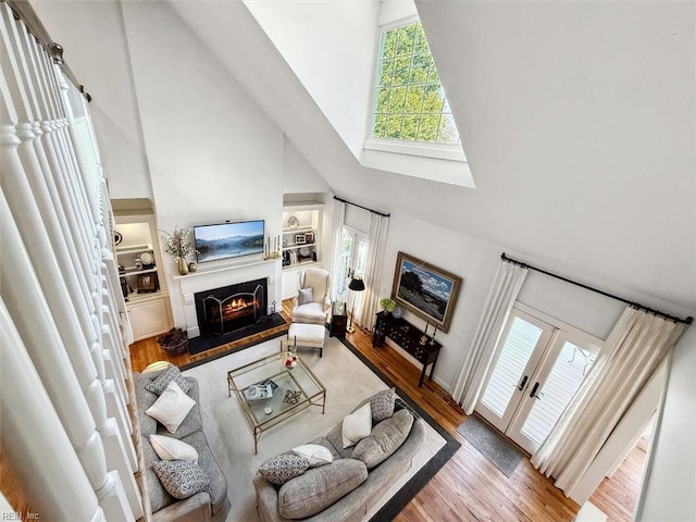 living area featuring plenty of natural light, wood finished floors, a lit fireplace, and built in features