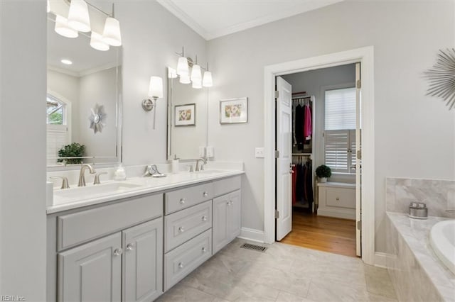 bathroom featuring a sink, double vanity, crown molding, and tiled bath