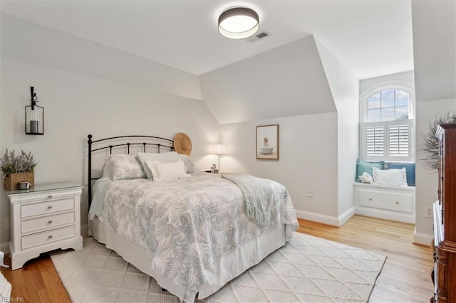 bedroom featuring visible vents, lofted ceiling, baseboards, and light wood finished floors