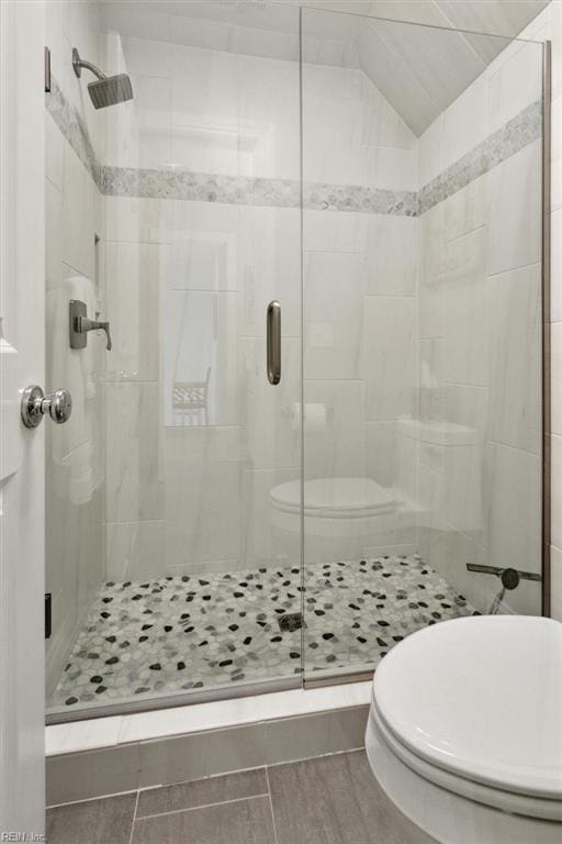 bathroom with vaulted ceiling, toilet, and a stall shower