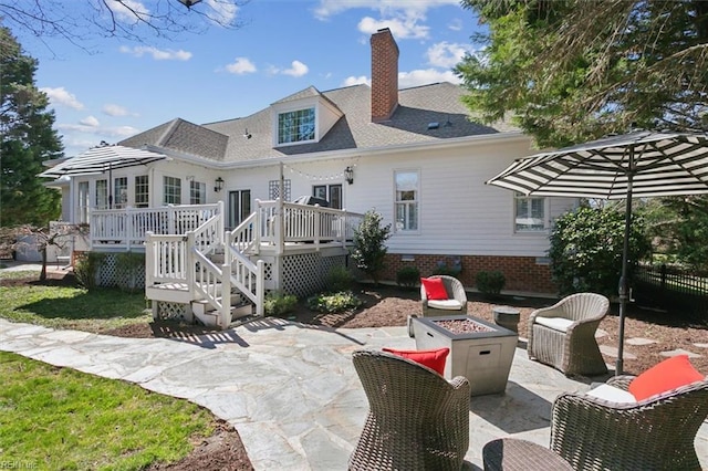 back of property with a deck, a patio, a chimney, and an outdoor fire pit