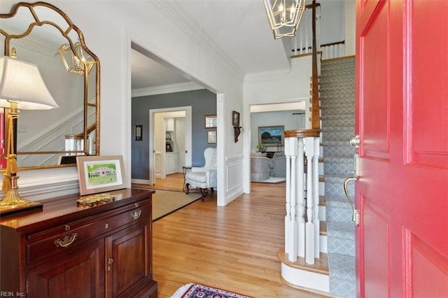 foyer with a chandelier, light wood-style floors, ornamental molding, and stairway