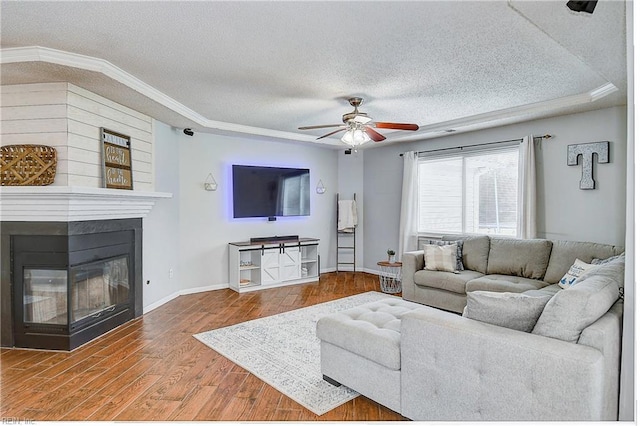 living area featuring a multi sided fireplace, a textured ceiling, wood finished floors, and ornamental molding