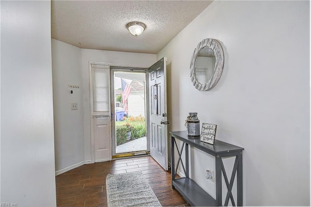 foyer entrance featuring dark wood finished floors, baseboards, and a textured ceiling