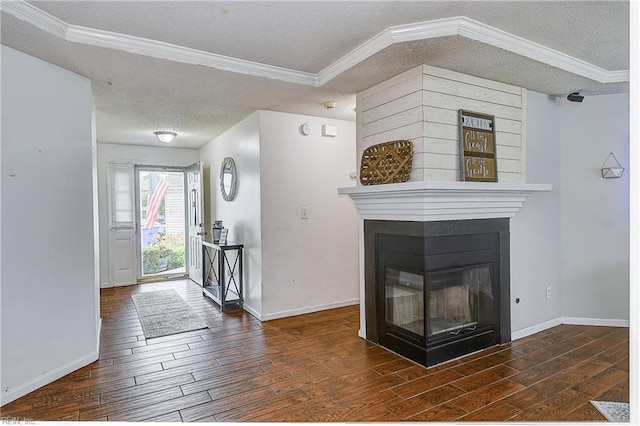 entryway with a multi sided fireplace, a textured ceiling, baseboards, and wood finished floors