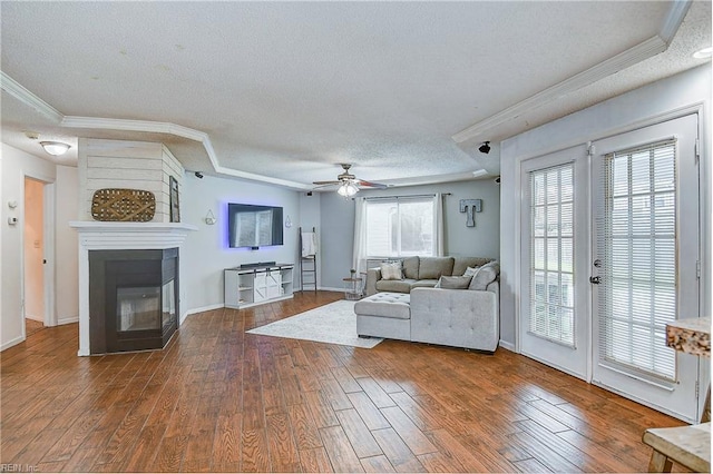 living room featuring crown molding, wood finished floors, a multi sided fireplace, and a textured ceiling